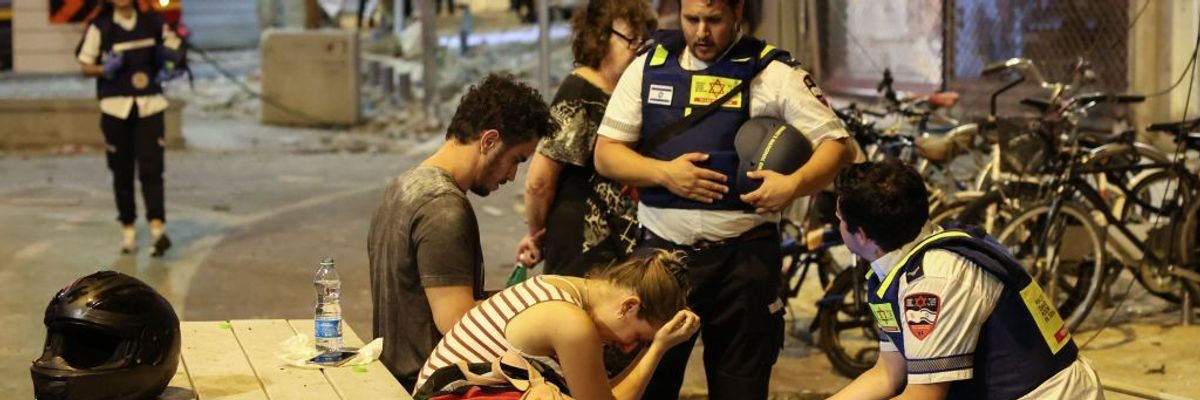 A young woman reacts as she speaks to Israeli rescuers in Tel Aviv, after a was hit by a rocket fired by Palestinian militants from the Gaza Strip on October 7, 2023.