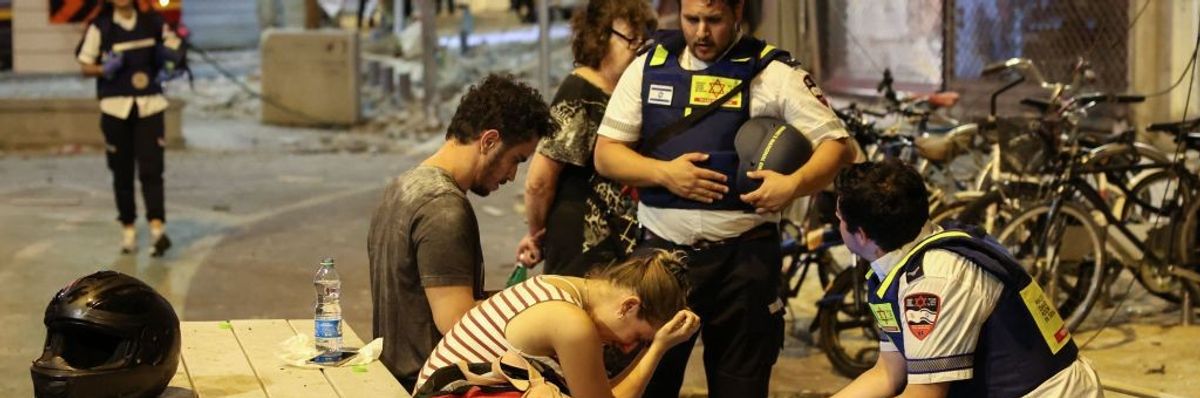 A young woman reacts as she speaks to Israeli rescuers in Tel Aviv, after a was hit by a rocket fired by Palestinian militants from the Gaza Strip on October 7, 2023.