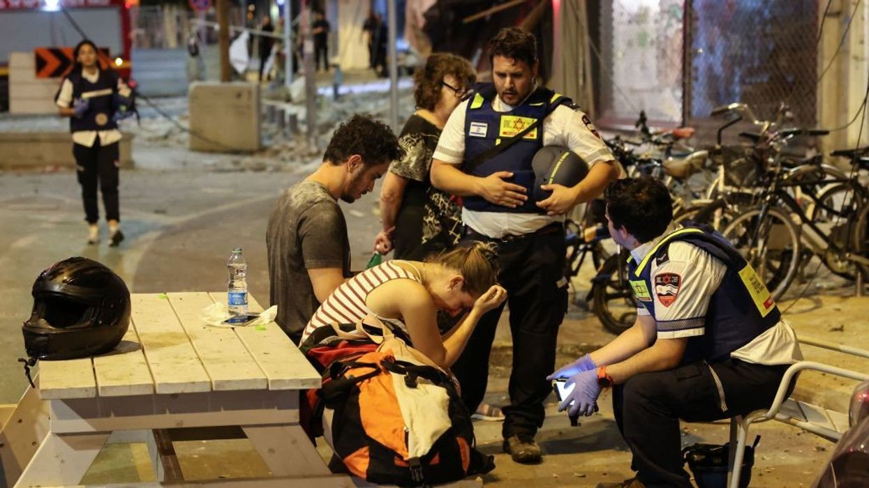 A young woman reacts as she speaks to Israeli rescuers in Tel Aviv, after a was hit by a rocket fired by Palestinian militants from the Gaza Strip on October 7, 2023.