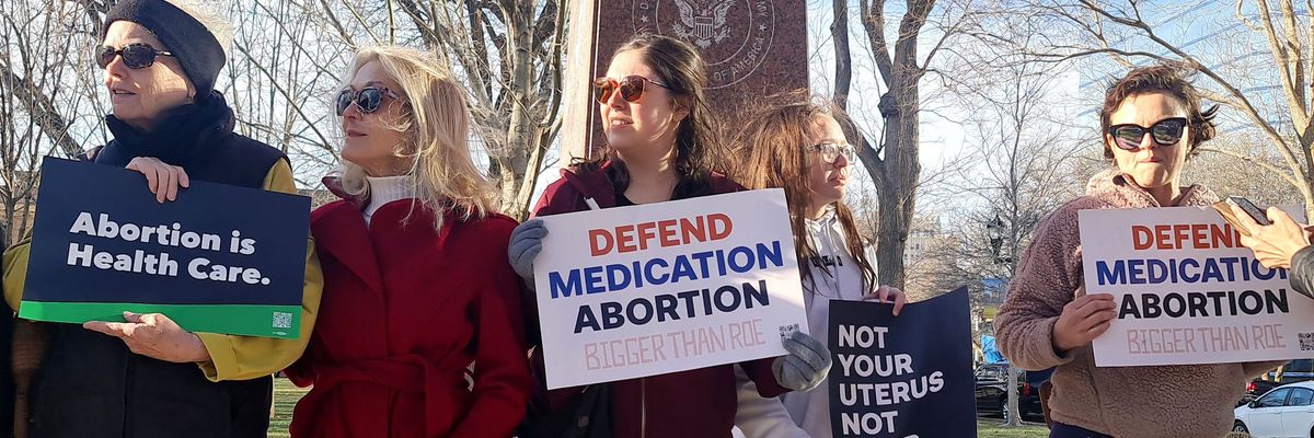 Abortion rights advocates carry signs supporting medication abortions.