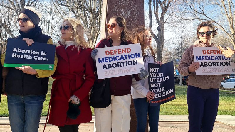 Abortion rights advocates carry signs supporting medication abortions.