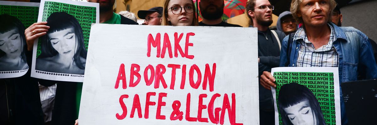 Abortion rights supporters hold banners outside a police station in Krakow