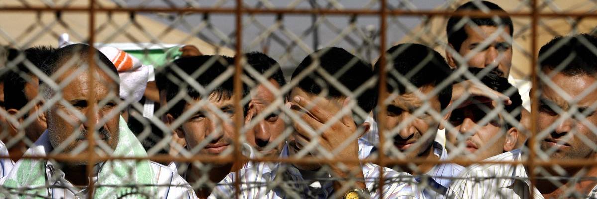 Abu Ghraib detainees behind chain-linked fence.
