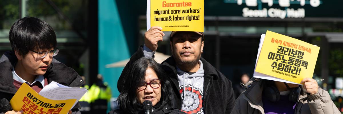 activist hold signs, and one person speaks into a microphone.
