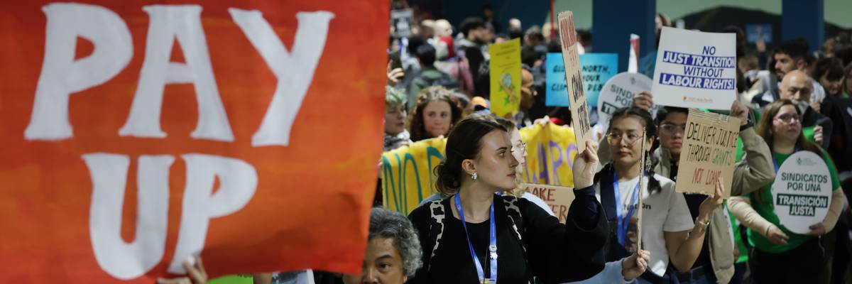 Activist holds sign saying, "Pay up," at COP29.