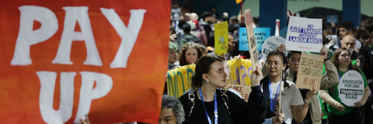 Activist holds sign saying, "Pay up," at COP29.