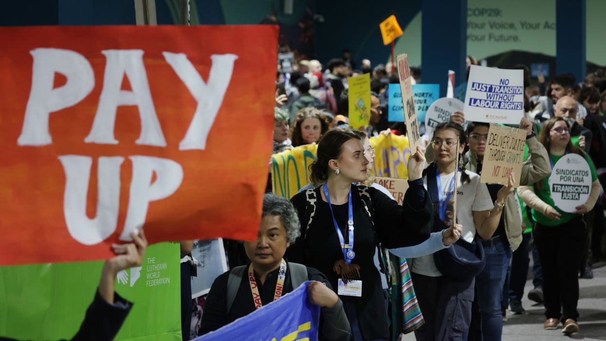 Activist holds sign saying, "Pay up," at COP29.