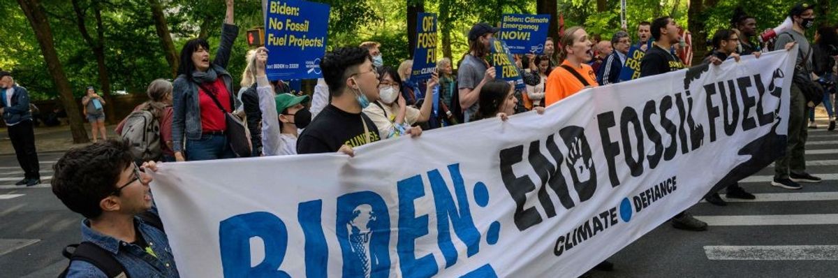 Activists carry a sign saying, "Biden: End Fossil Fuels."