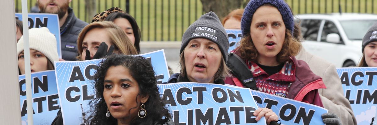 Activists carrying blue signs reading, "Act on climate.'