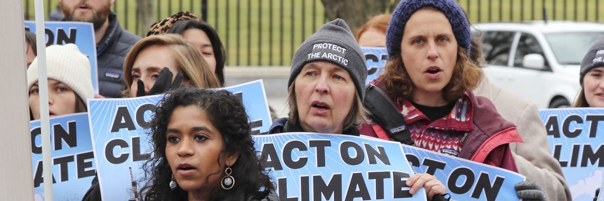 Activists carrying blue signs reading, "Act on climate.' 