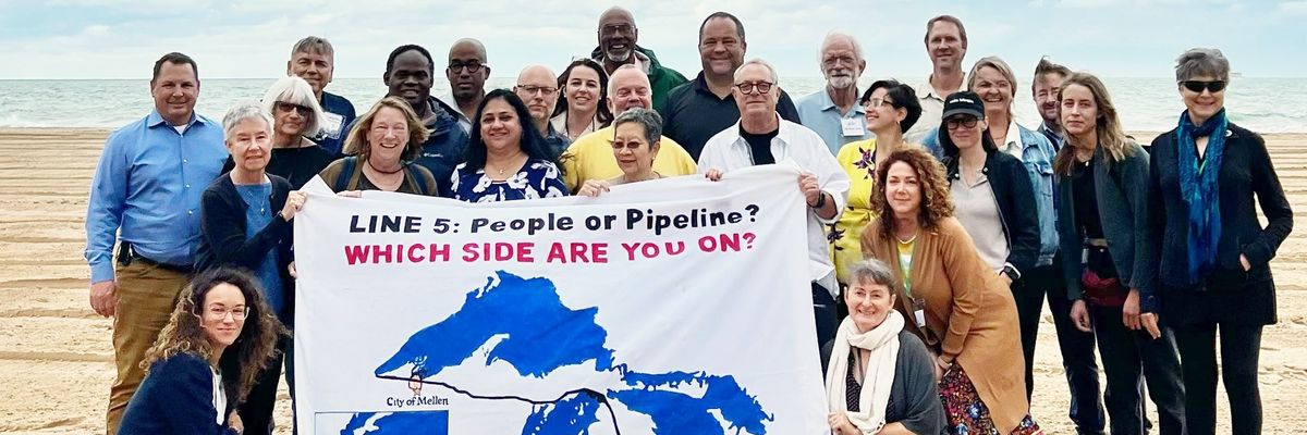 Activists gather around a sign reading, "Line 5: people or pipeline? Which side are you on?"
