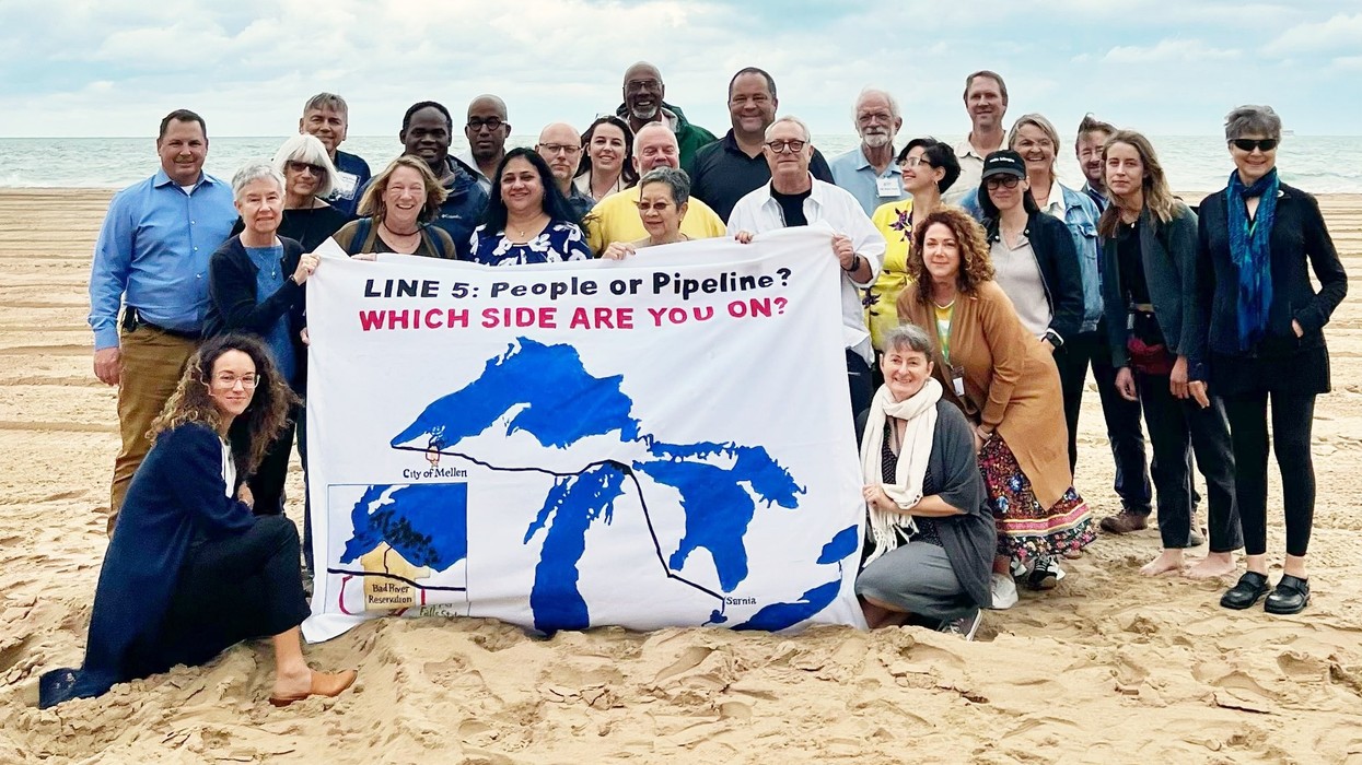 Activists gather around a sign reading, "Line 5: people or pipeline? Which side are you on?"