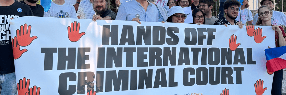 Activists hold a banner reading "Hand Off the International Criminal Court"
