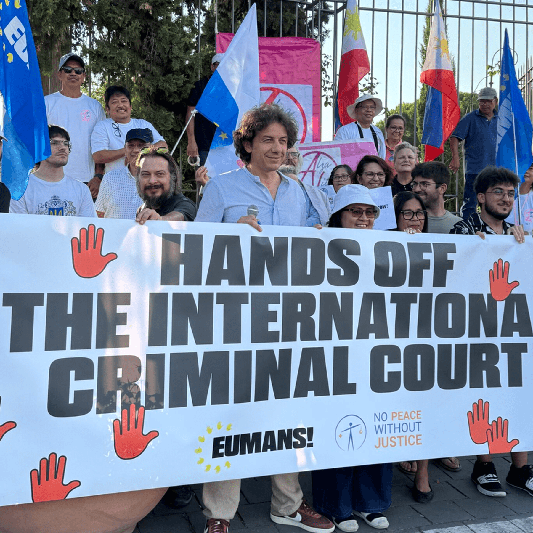 Activists hold a banner reading "Hand Off the International Criminal Court"