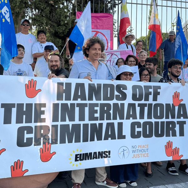 Activists hold a banner reading "Hand Off the International Criminal Court"
