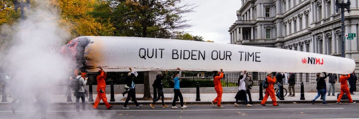 Activists hold a giant mock joint saying "quit Biden our time" as they march in Washintgon, D.C.
