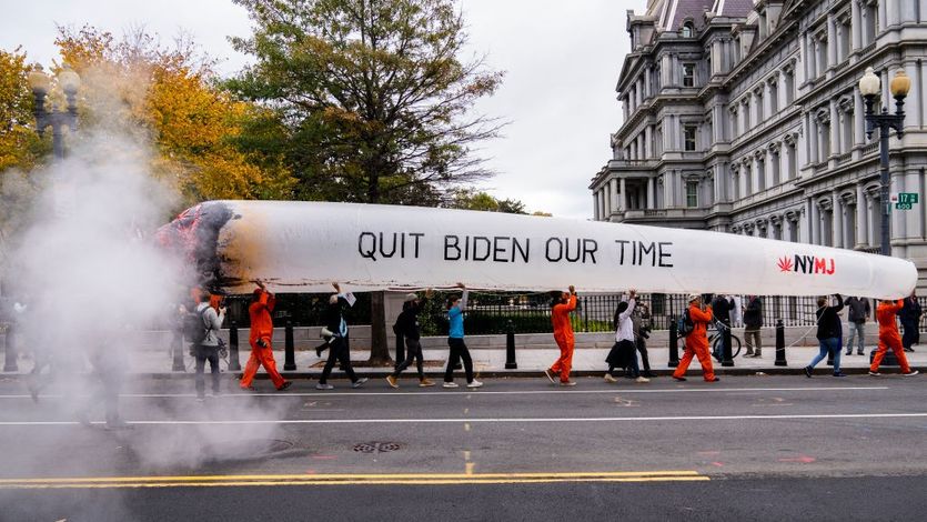 Activists hold a giant mock joint saying "quit Biden our time" as they march in Washintgon, D.C.