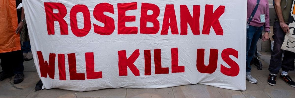 Activists hold a white sign reading "Rosebank will kill us."