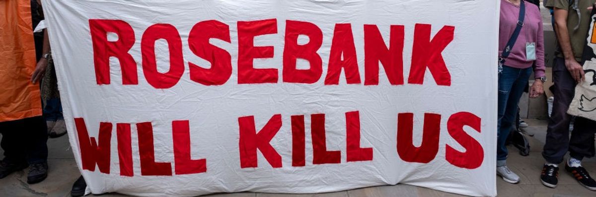 Activists hold a white sign reading "Rosebank will kill us". 