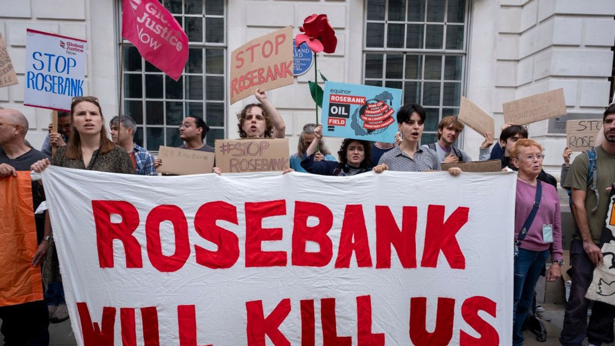 Activists hold a white sign reading "Rosebank will kill us".