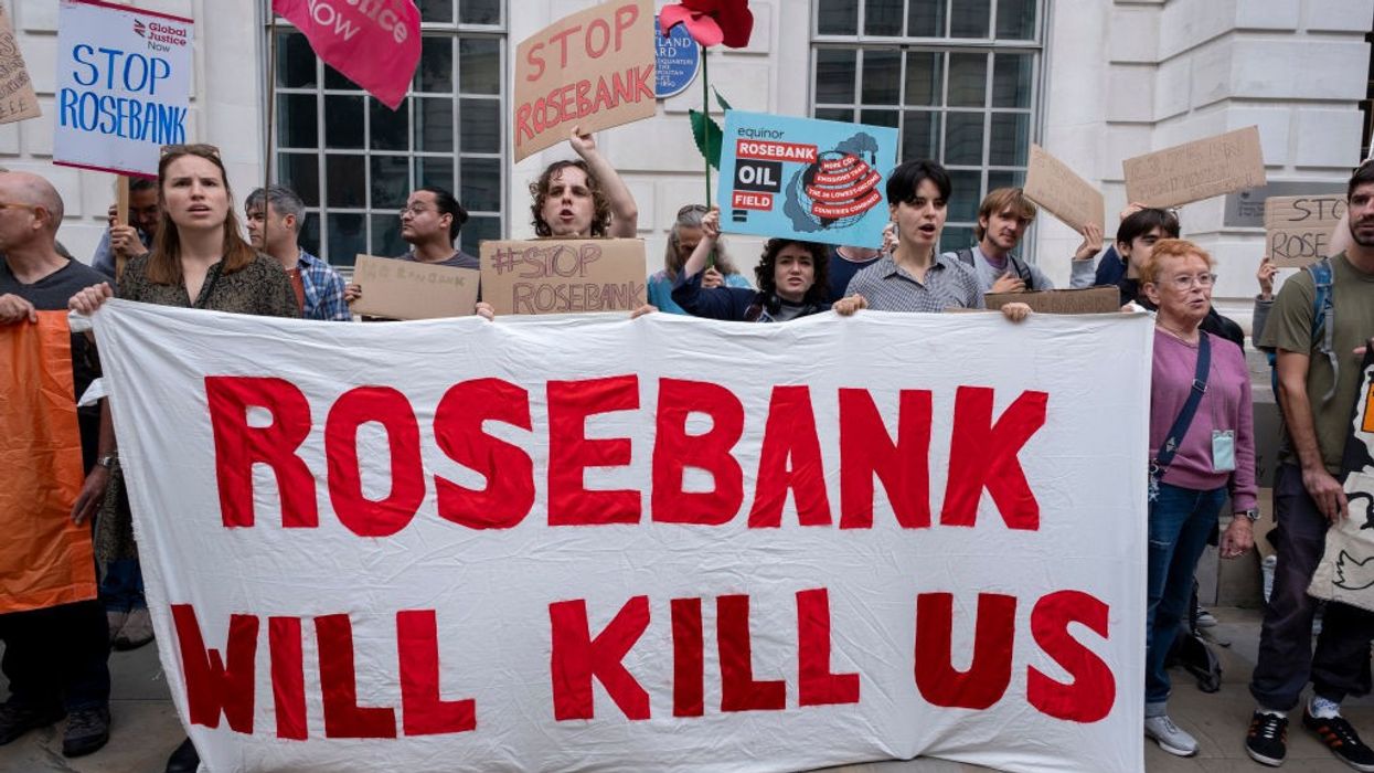 Activists hold a white sign reading "Rosebank will kill us."
