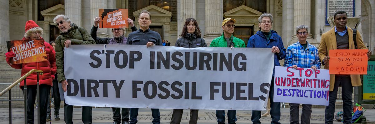 Activists hold banner saying "Stop Insuring dirty fossil fuels."