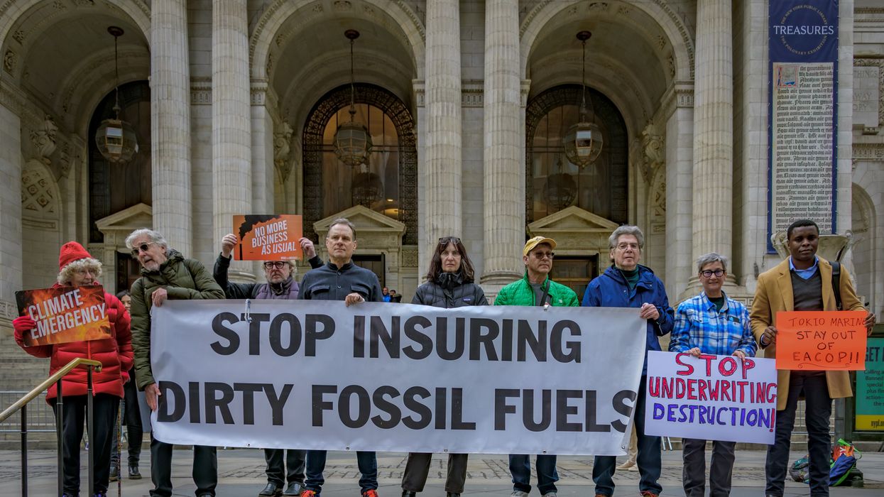 Activists hold banner saying "Stop Insuring dirty fossil fuels."