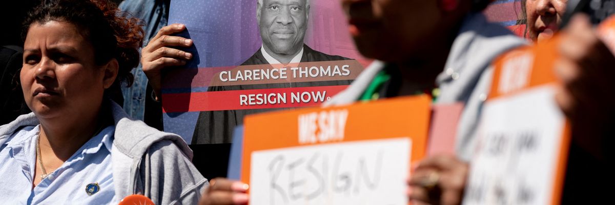Activists hold signs calling on Supreme Court Justice Clarence Thomas to resign