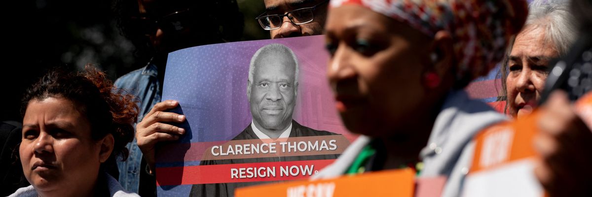 Activists hold signs calling on Supreme Court Justice Clarence Thomas to resign