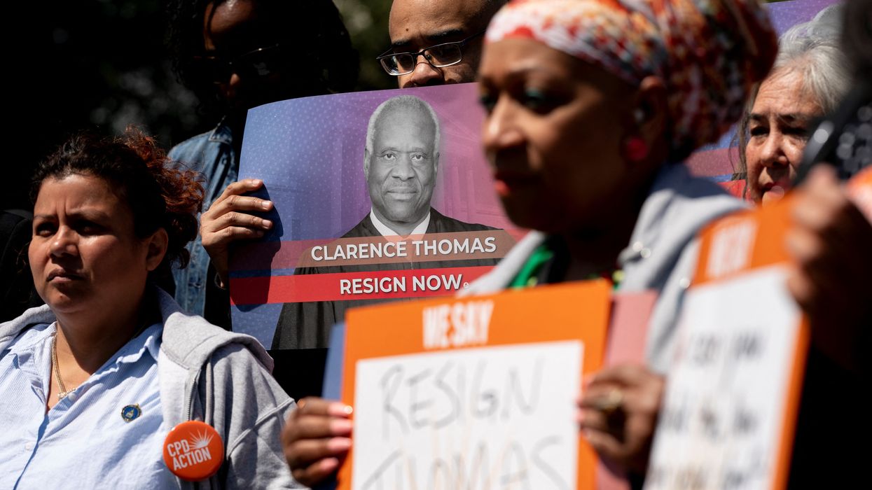 Activists hold signs calling on Supreme Court Justice Clarence Thomas to resign