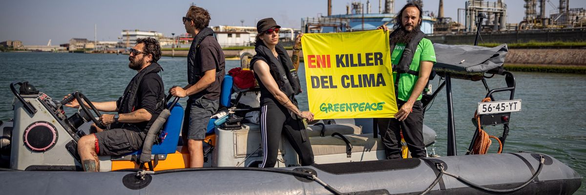 Activists in a rubber motor boat with a sign reading, "ENI climate killer" in Italian.