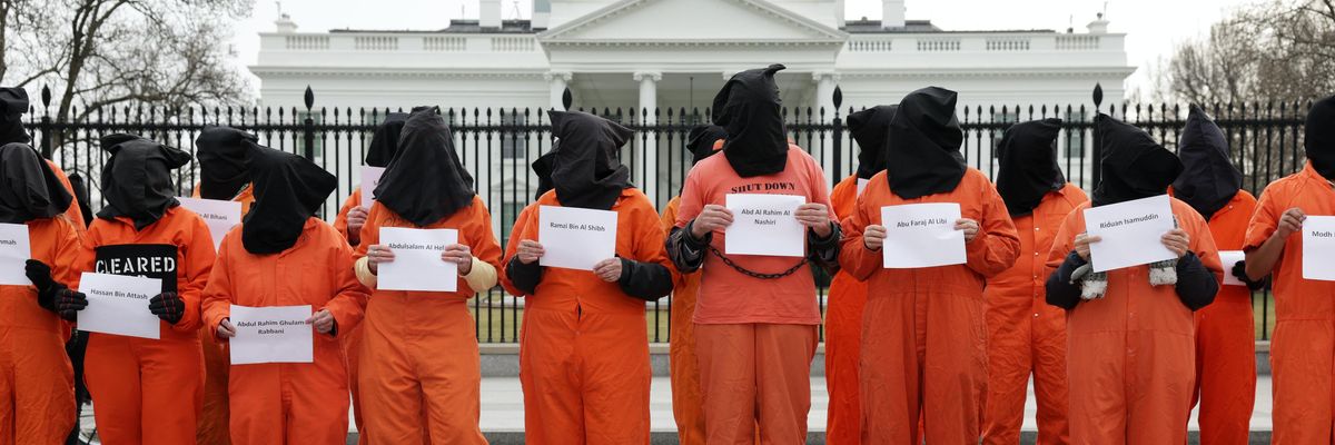 Activists in orange jumpsuits protest in front of the White House.
