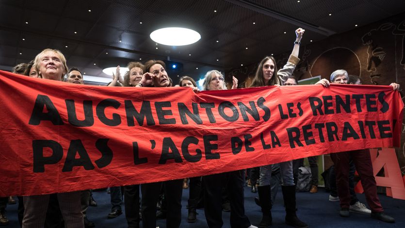 Activists in Switzerland celebrate while holding a red banner.