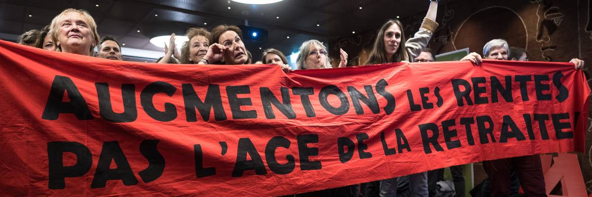 Activists in Switzerland celebrate while holding a red banner.