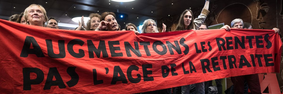 Activists in Switzerland celebrate while holding a red banner.