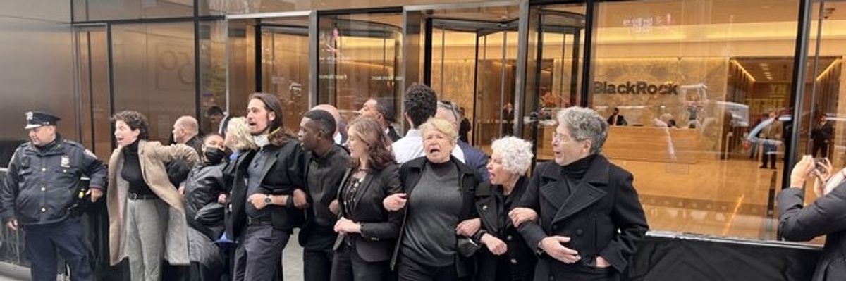 Activists link arms in front of a building.