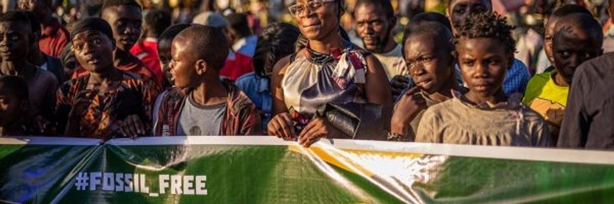 Activists march behind a banner reading, "Fossil Free."