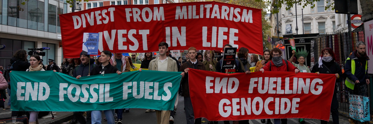 Activists march in London with banners reading, "Divest from militarism, invest in life," "end fossil fuels," and "end fueling genocide."