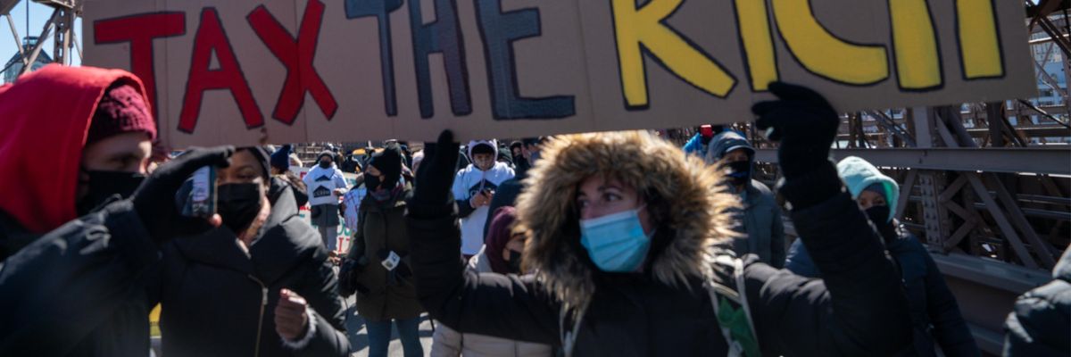 Activists march with a "Tax the Rich" sign