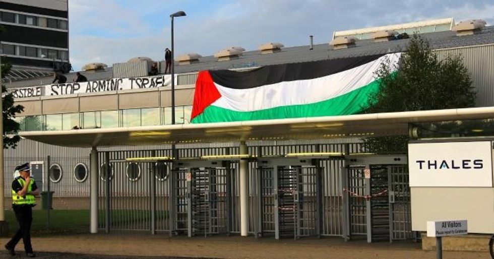 Activists occupying the roof drape banner over the side of the factory. (Photo Couresty of Glasgow Palestine Action)