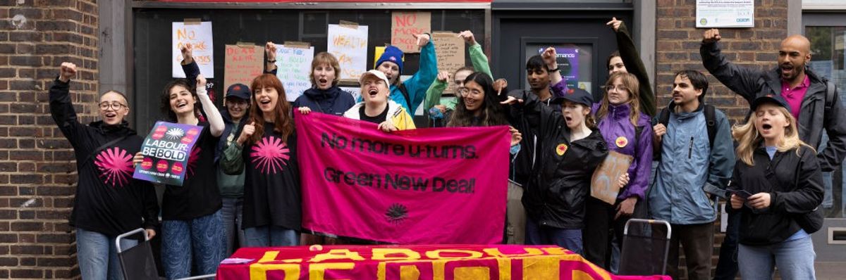 Activists surround a pink sign reading, "No More U-Turns. Green New Deal."