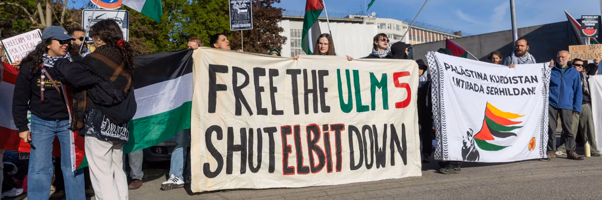 Activists unfurl a banner in solidarity with jailed pro-Palestine activists in Germany.