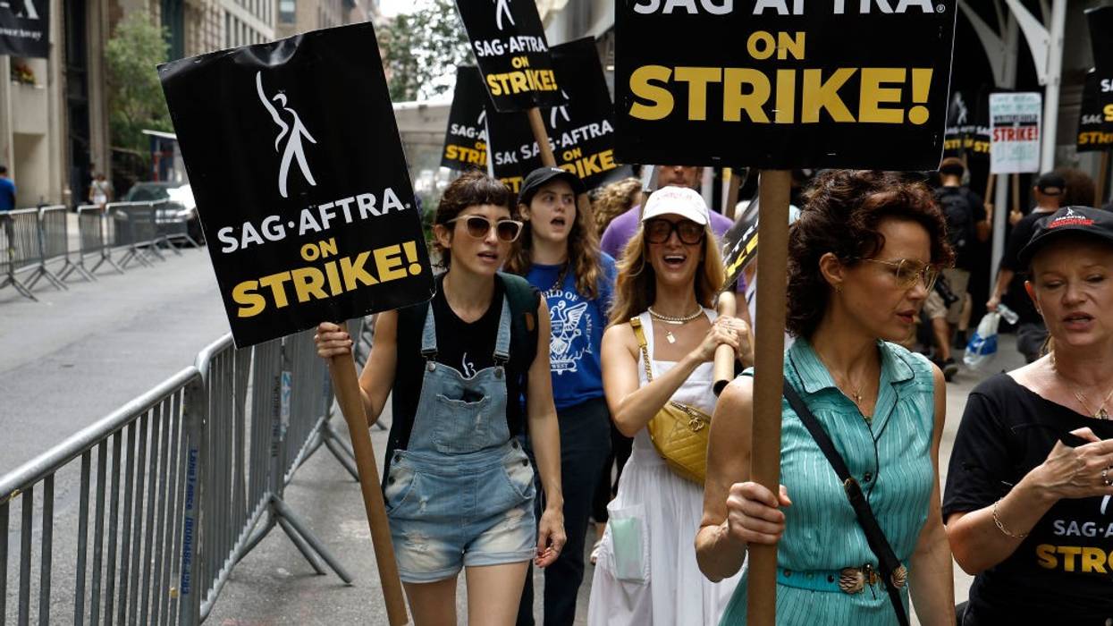 Actors picket carrying signs saying, "SAG-AFTRA on strike!"