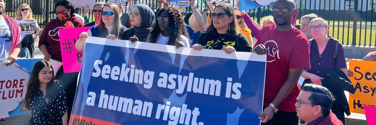Advocates hold signs in support of asylum rights