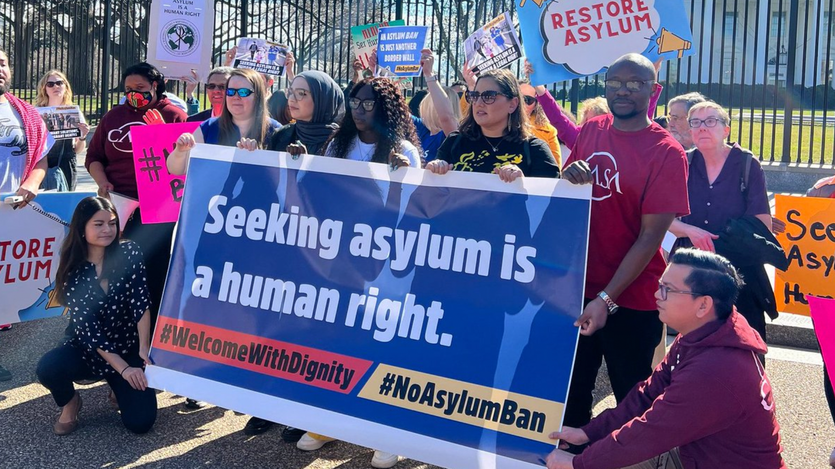 Advocates hold signs in support of asylum rights