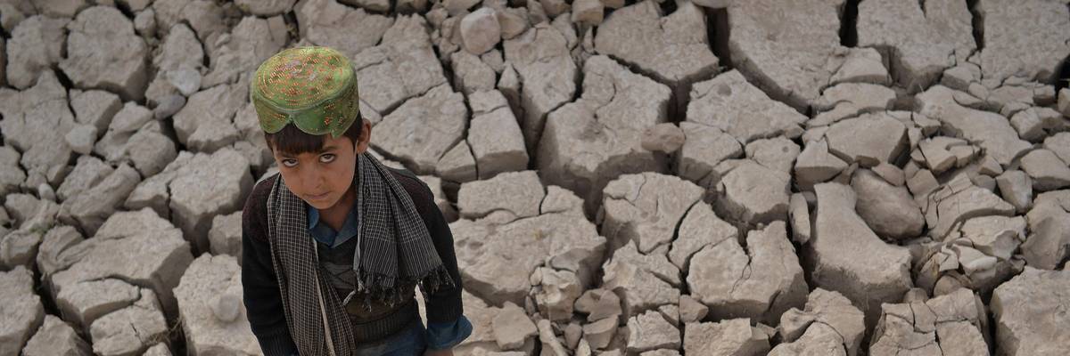 Afghan boy standing in drought-stricken flats