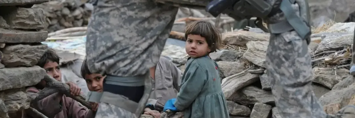 Afghan child looks out behind US soldier