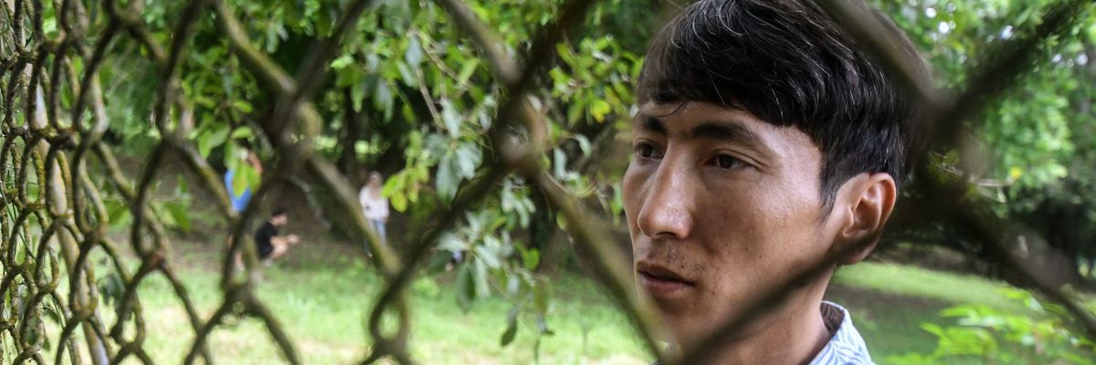 Afghan Mohammad Saber Asadi talks to reporters through a fence