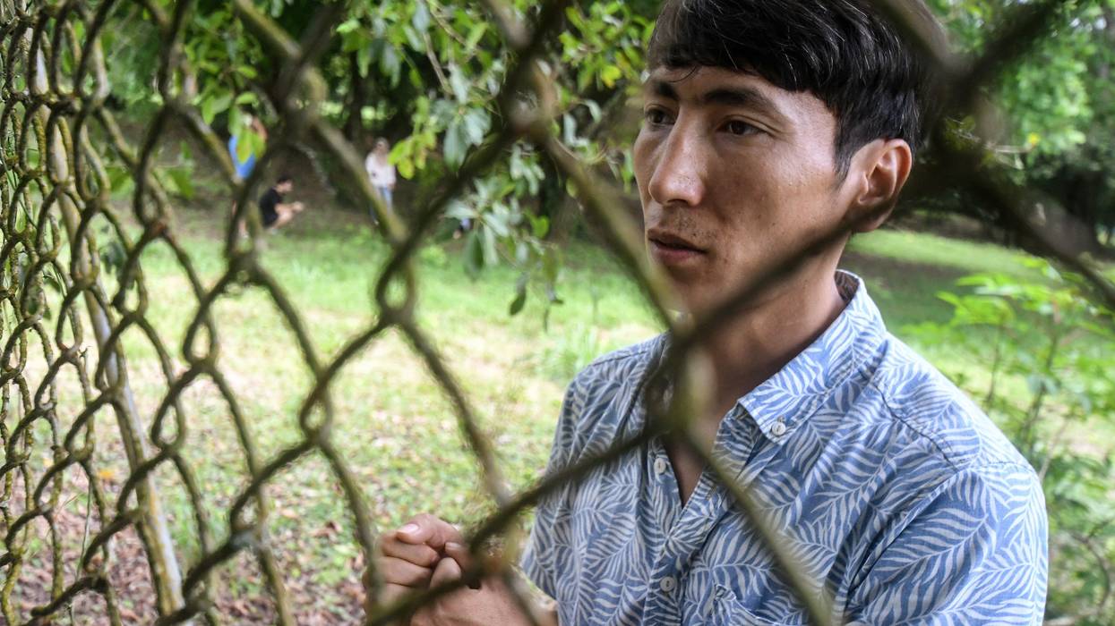 Afghan Mohammad Saber Asadi talks to reporters through a fence