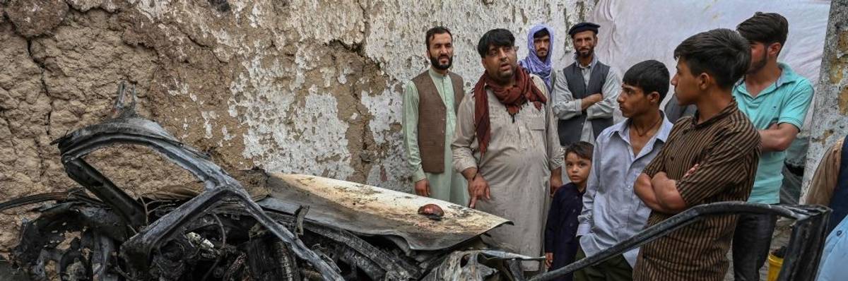 Afghan residents and family members of the victims gather next to a vehicle destroyed by a US drone airstrike in Kabul on August 30, 2021.